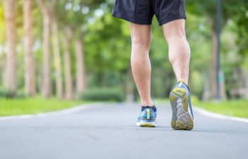 Young adult male in sport shoes running in the park outdoor, runner man jogging and walking on the road at morning, leg muscles of Athlete. Exercise, wellness, healthy lifestyle and workout concepts